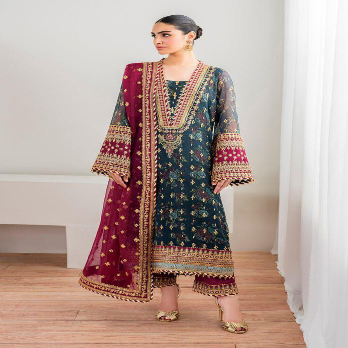 Woman wearing a traditional outfit with a blue and red design in a minimalistic setting