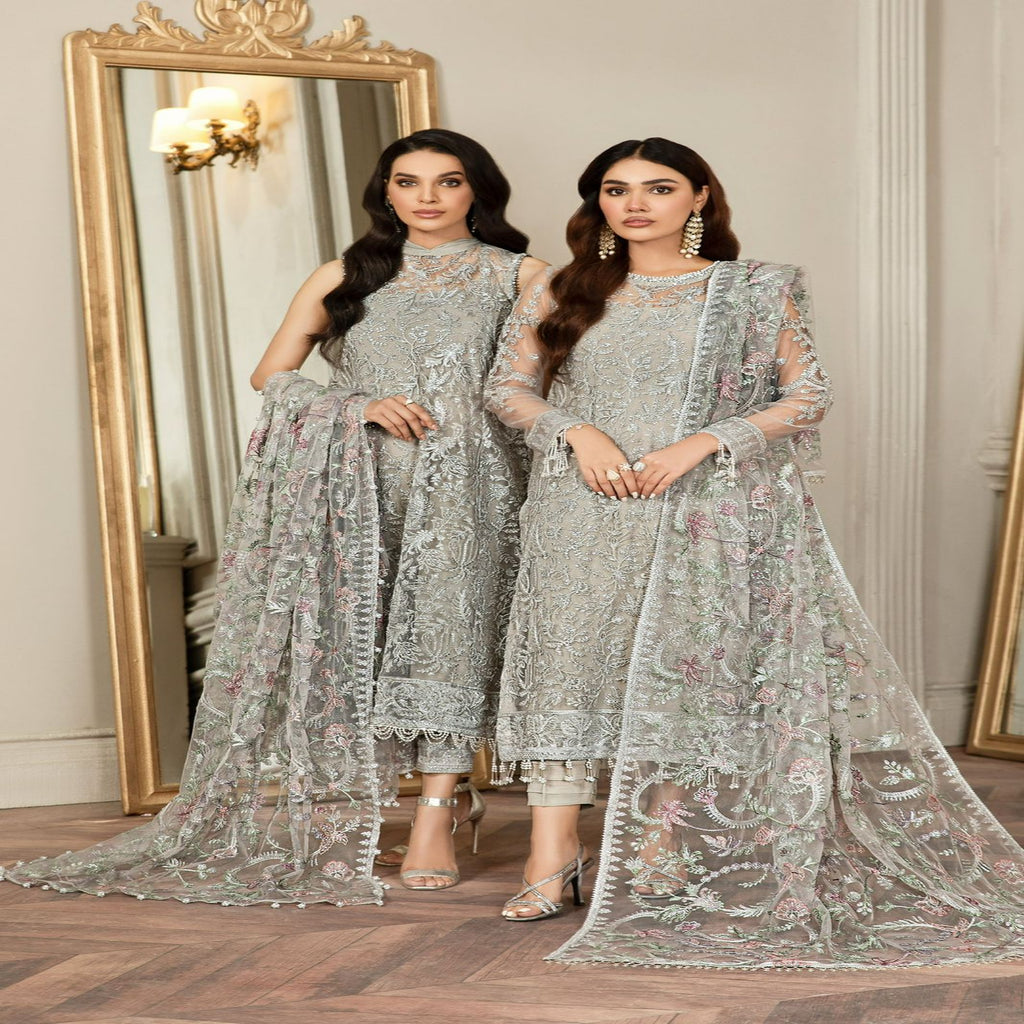 Two women in silver embroidered traditional outfits standing in front of a mirror.