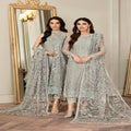 Two women in silver embroidered traditional outfits standing in front of a mirror.