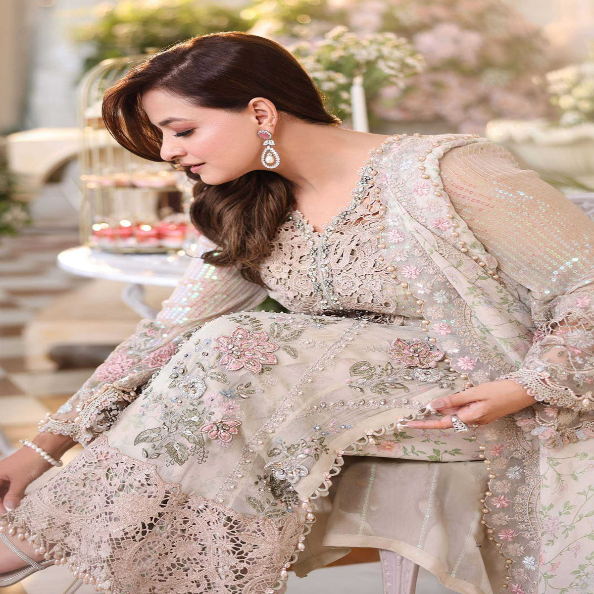 Woman in a floral embroidered outfit sitting outdoors with blurred background