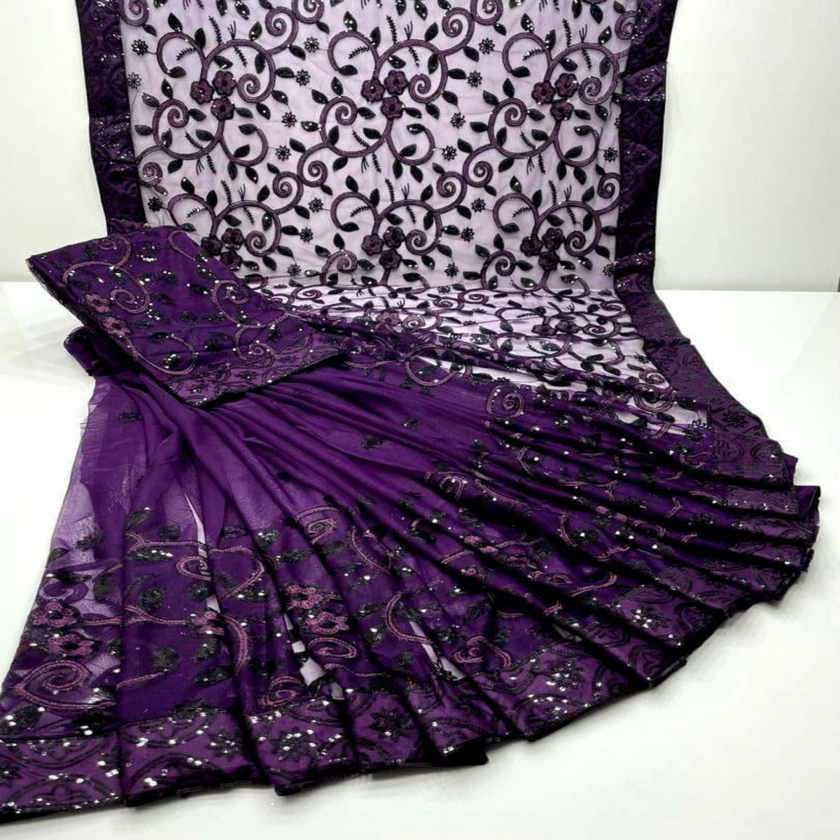 Purple and black embroidered georgette saree with a matching blouse and dupatta, displayed on a white surface.