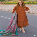 Woman in a brown embroidered dress with a colorful scarf on a road with flowers in the background