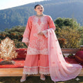 Woman in a pink embroidered outfit standing outdoors with mountains in the background