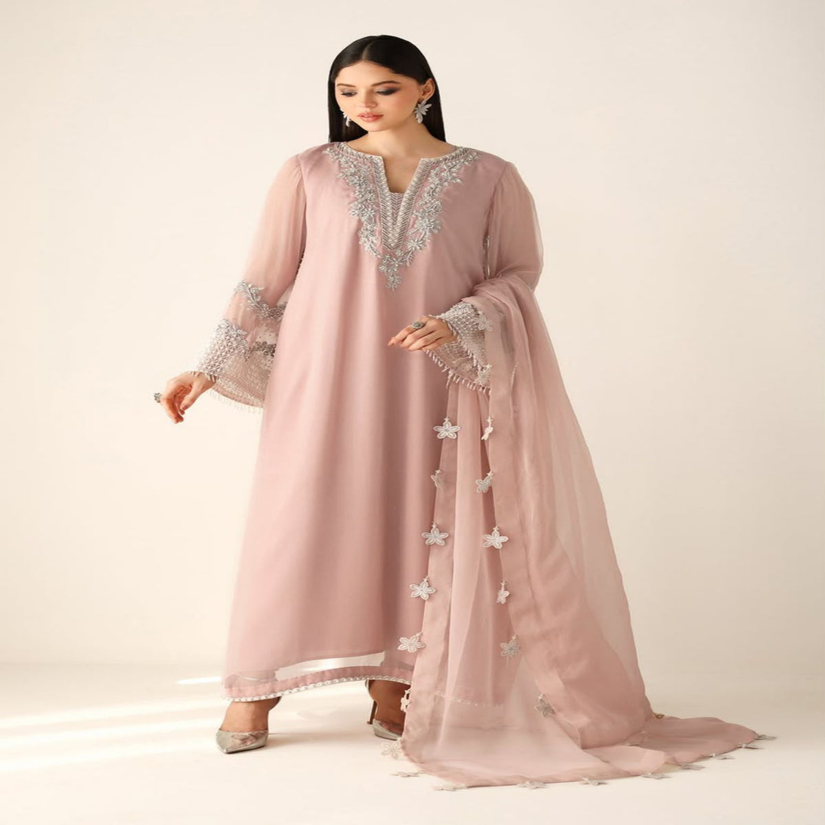 Woman wearing a pink embroidered dress on a white background
