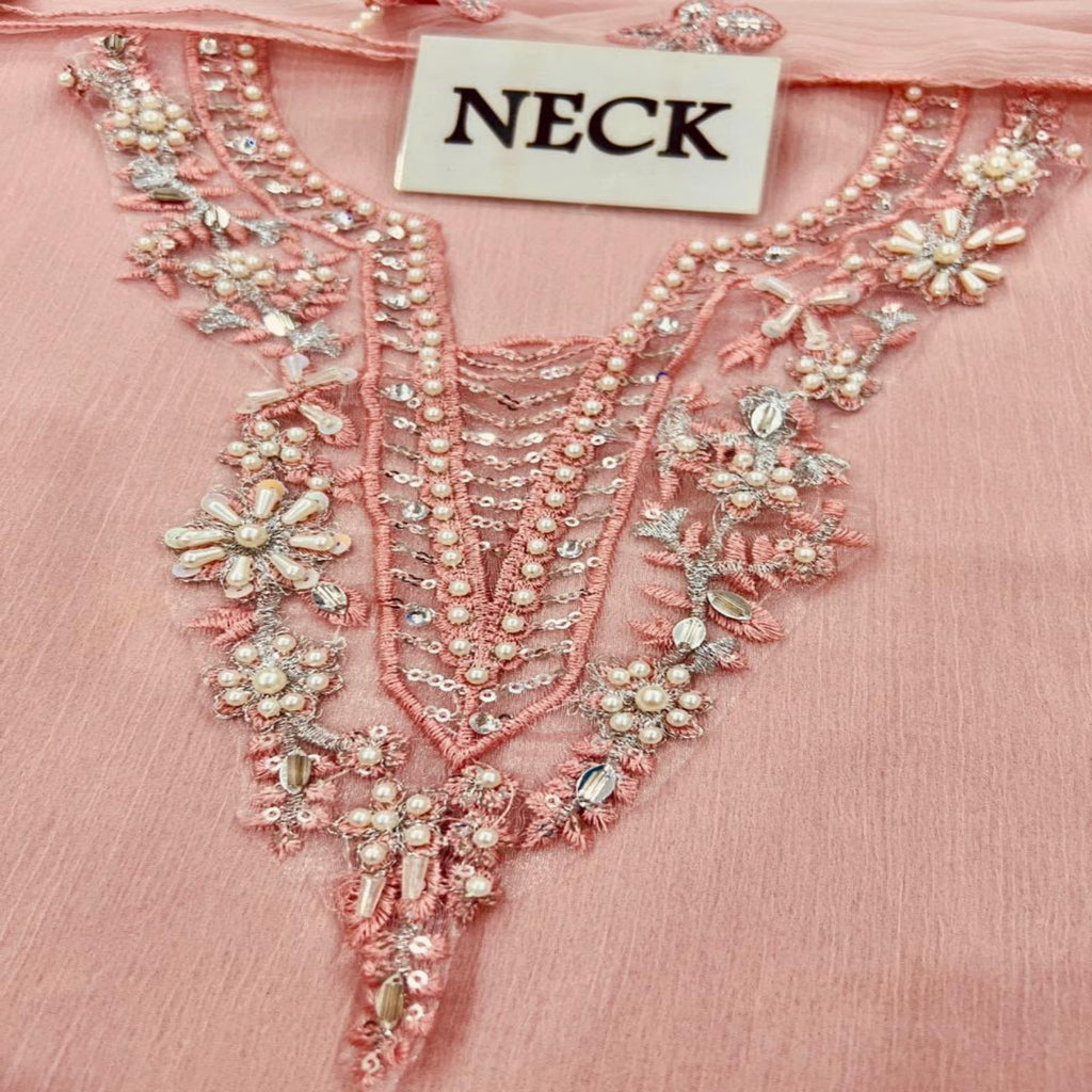 A close-up of a pink embroidered neckline on a matching garment, featuring intricate beadwork, sequins, and floral embellishments. A small white tag at the top reads 'NECK'.
