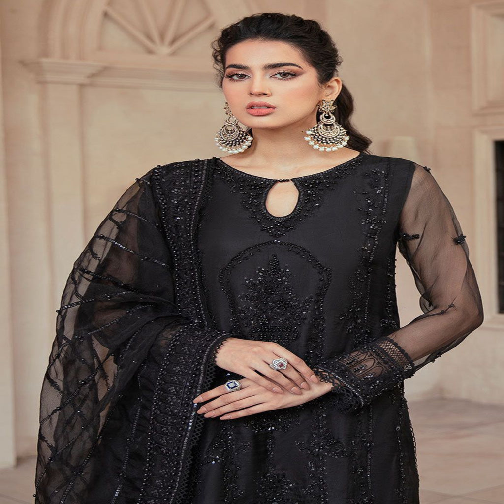 Woman wearing a black embroidered outfit with sheer sleeves in an indoor setting