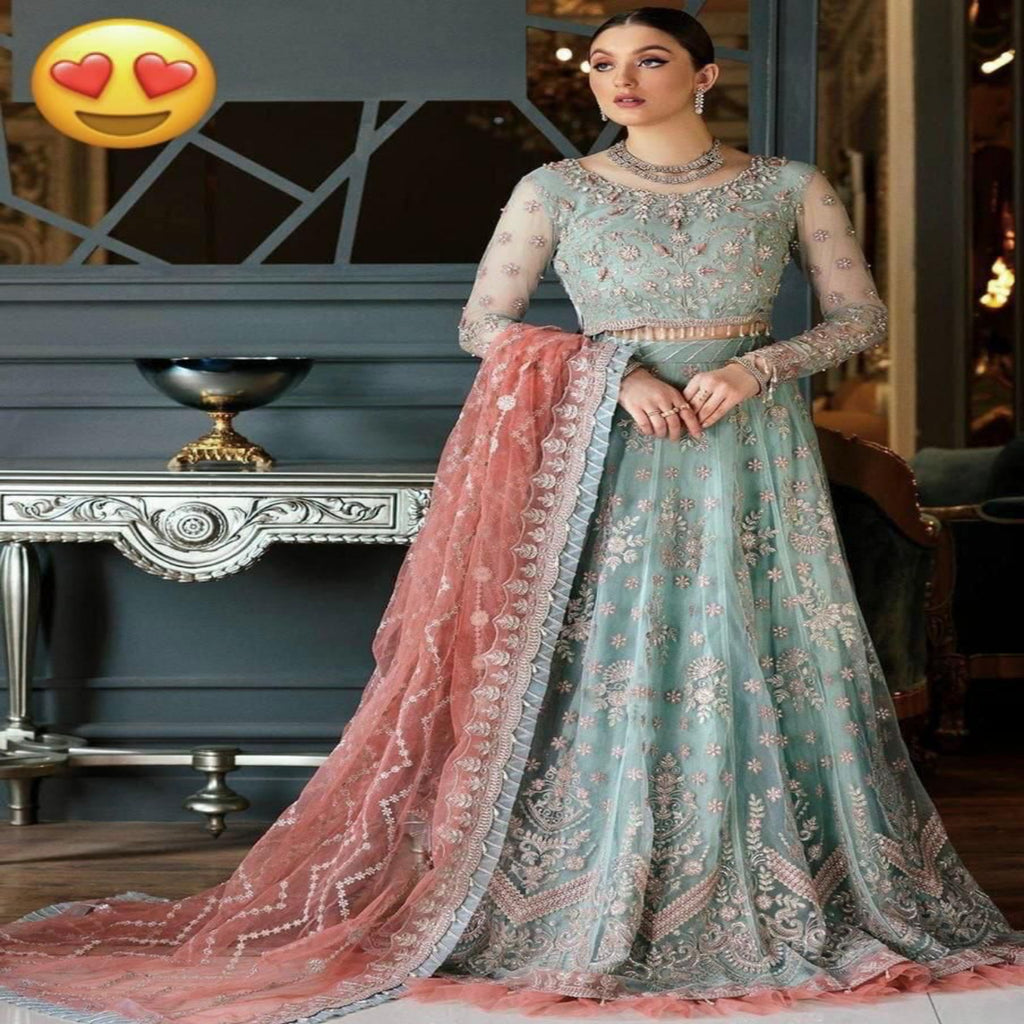 Woman in a light blue and pink embroidered traditional outfit with a heart emoji above.