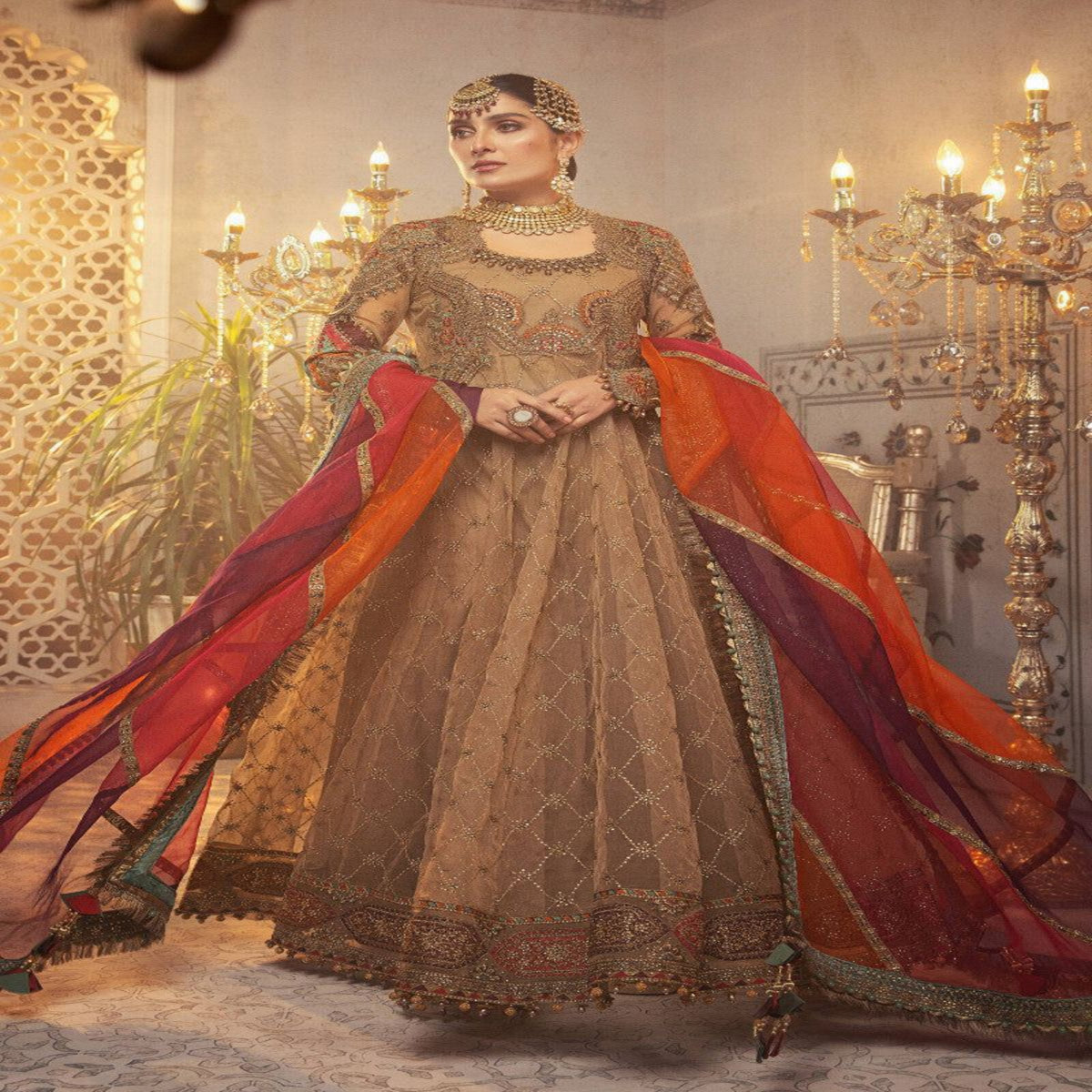 Woman in a traditional outfit with a red dupatta in an ornate indoor setting