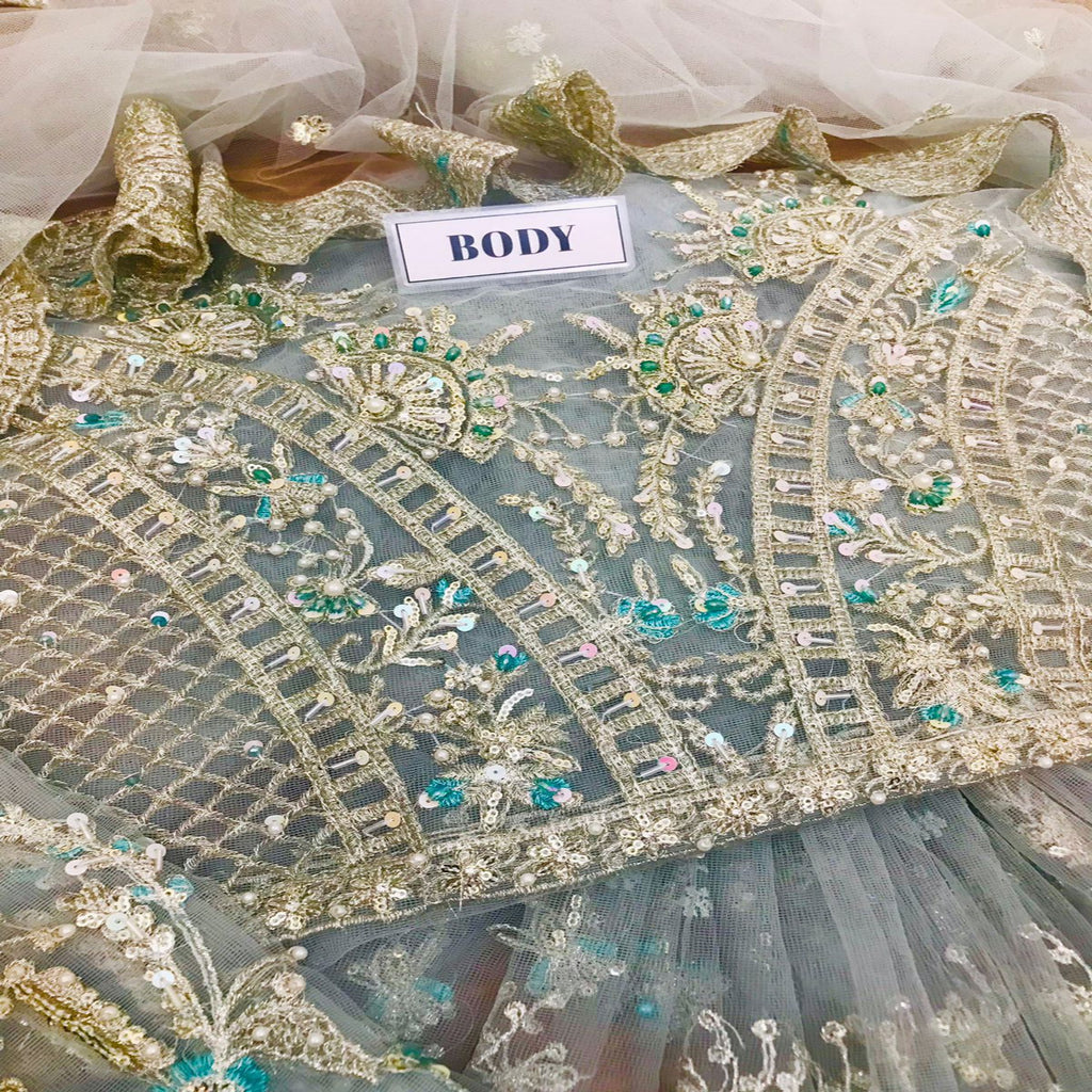 Decorative fabric with gold embroidery and green beads on a white background