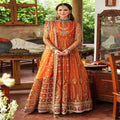 Woman in an orange and gold traditional outfit standing in a decorated room.