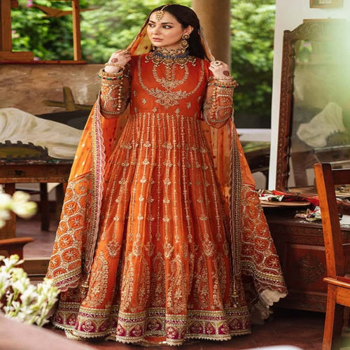 Woman in an orange and red embroidered traditional outfit indoors.