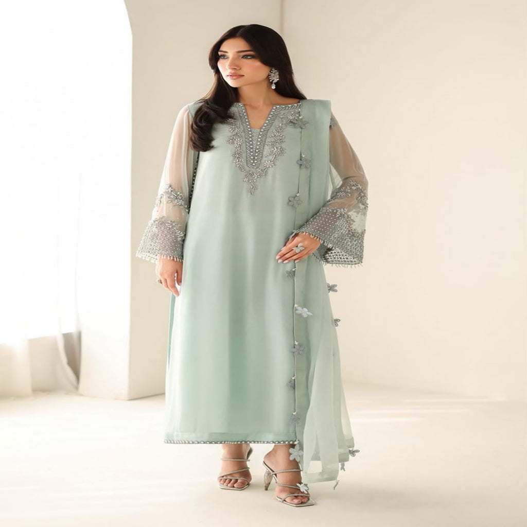 Woman wearing a light green embroidered outfit with a matching dupatta on a white background