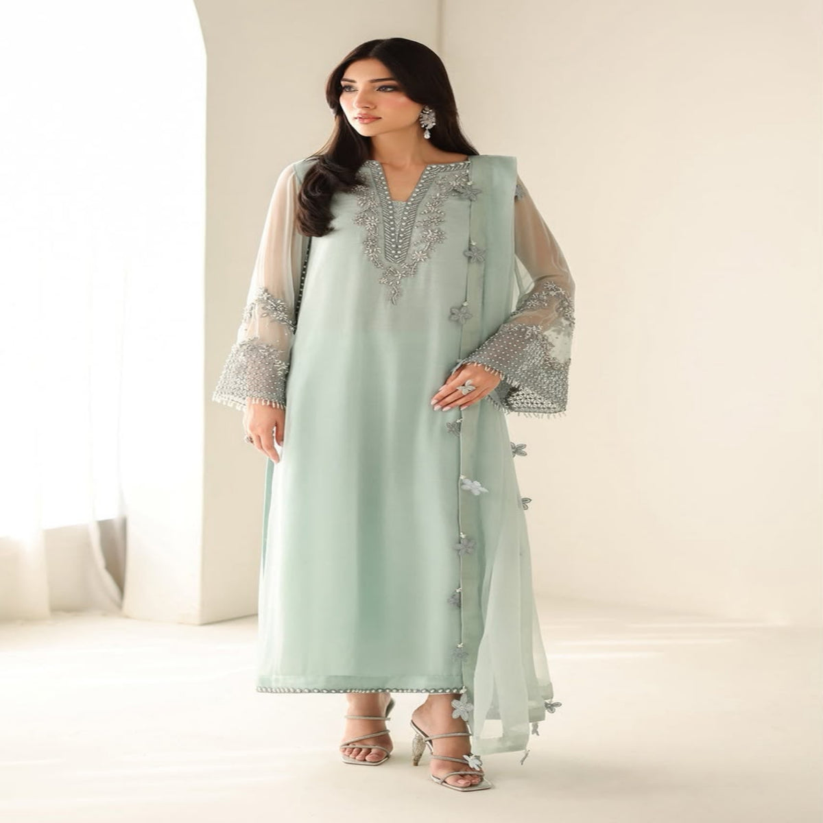 Woman wearing a light green embroidered outfit with a matching dupatta on a white background