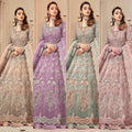 Four women modeling traditional embroidered Anarkali gowns side by side in different colors: beige, lavender, mint green, and dusty pink. Each gown features intricate floral embroidery, a long sleeve, and a matching dupatta, set against a warm beige indoor background.